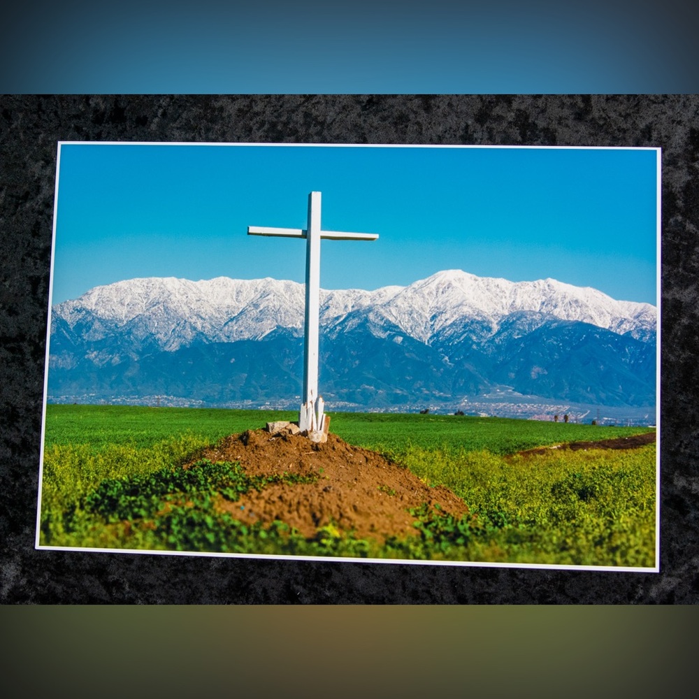 13” x 19” photograph print of cross in field and snow covered mountains.